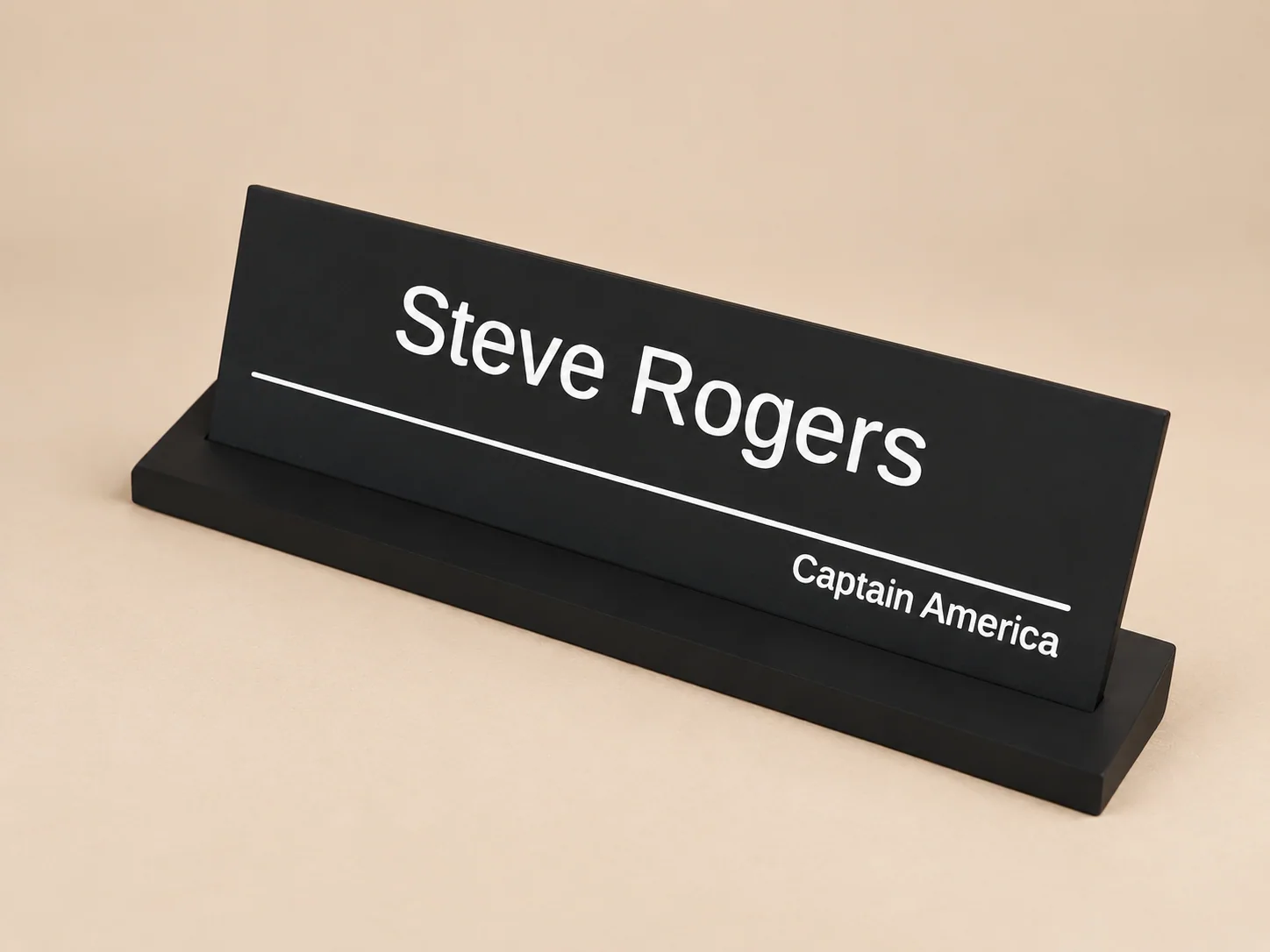 Targhetta nera da scrivania con supporto e scritte Steve Rogers e Captain America, su sfondo beige neutro